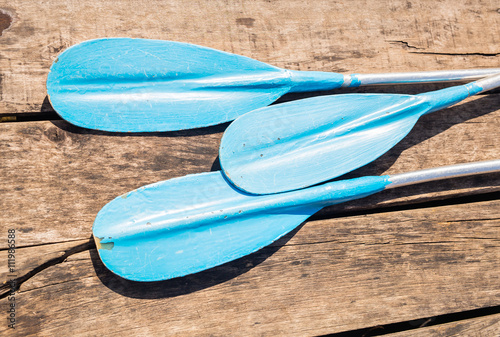 Blue plastic kayak paddle on wooden background