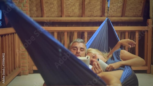couple lying together on hammock reading relaxing at night before go to sleep photo