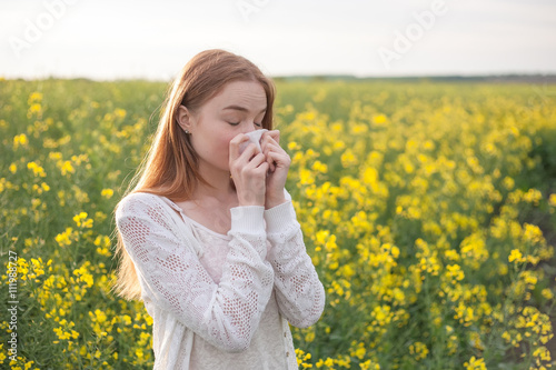 Pollen allergy, girl sneezing in a field of flowers