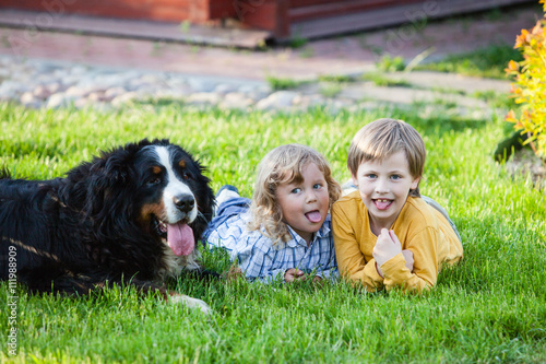 funny children lying on the grass with bernese mountain dog

