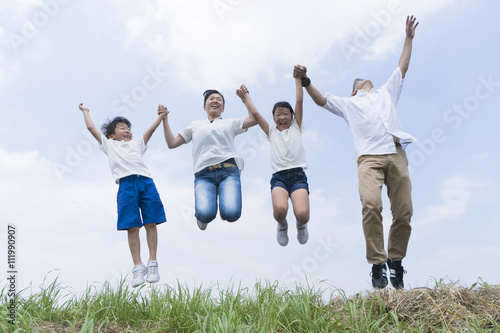 家族 4人 ジャンプ 飛ぶ 転ぶ 青空 外 春 小学生 幼稚園児 親ミドル世代