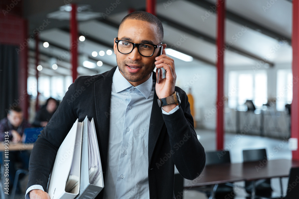 Bisnessman carrying folders and talking on the phone Bisnessman carrying folders and talking on the phone