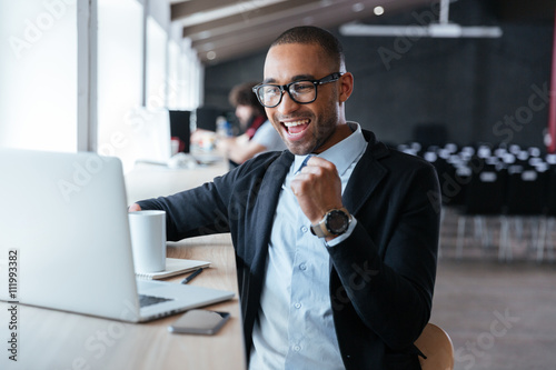 Handsome young businessman celebrating success with arms raised