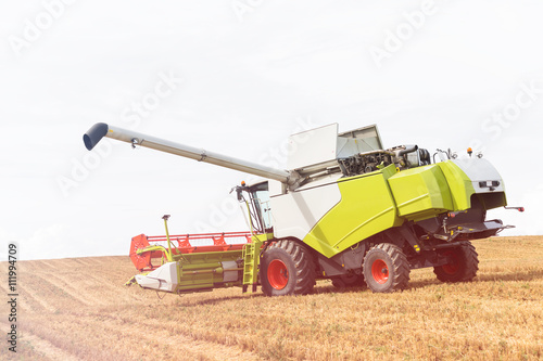 Modern combine harvester on stubble field at end of summer