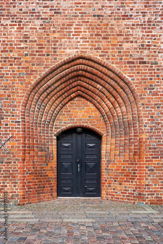 The entrance door of black painted wood, in the church tower build from red bricks, of Elsinore Cathedral in Denmark