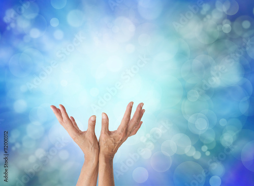 Energy worker with cooling blue energy - Blue bokeh effect radiating out from a light central area and female upwards reaching open hands with plenty of copy space