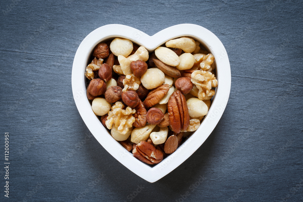 Heart shape bowl filled with mixed raw nuts Heart shape bowl filled with mixed raw nuts