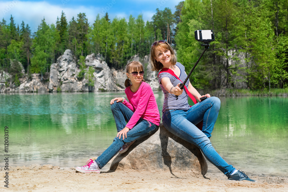 Mother and daughter are doing Selfe on the shore of Piskovna lake. National Park of Adrspach-Teplice rocks. Rock Town. Czech Republic.