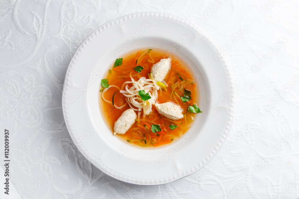 Chicken soup with noodles and vegetables in white bowl Chicken soup with noodles and vegetables in white bowl