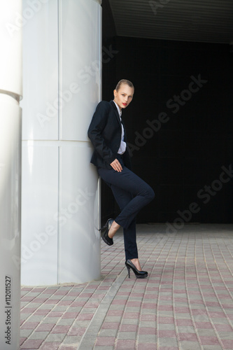Attractive woman in suit posing near white column