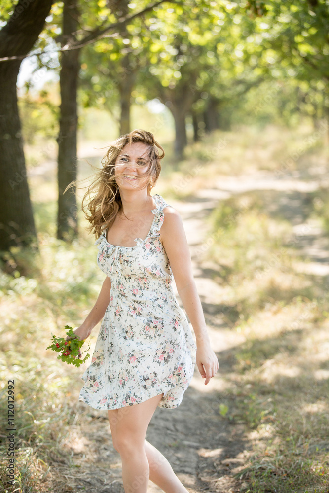 Girl jumping, dancing, spinning in an oak alley. The wind blew her hair and dress. Bright and sunny picture.Fain art film.