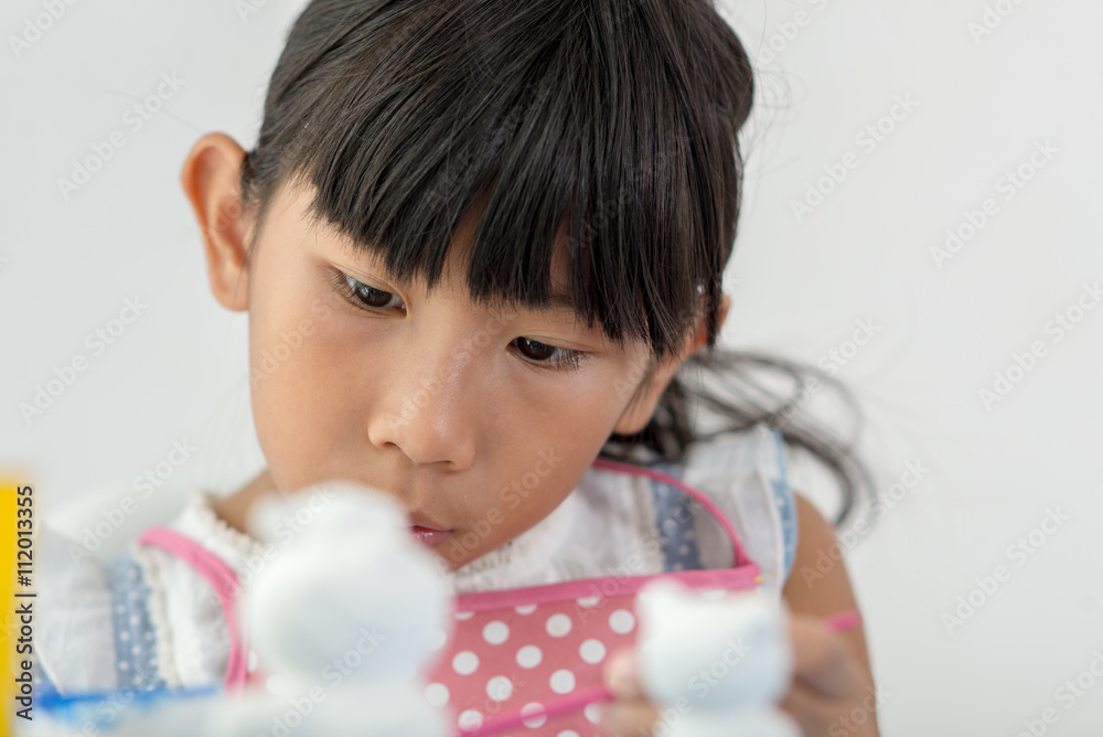 Asian child paints the colors of white plaster doll toys on the Asian child paints the colors of white plaster doll toys on the