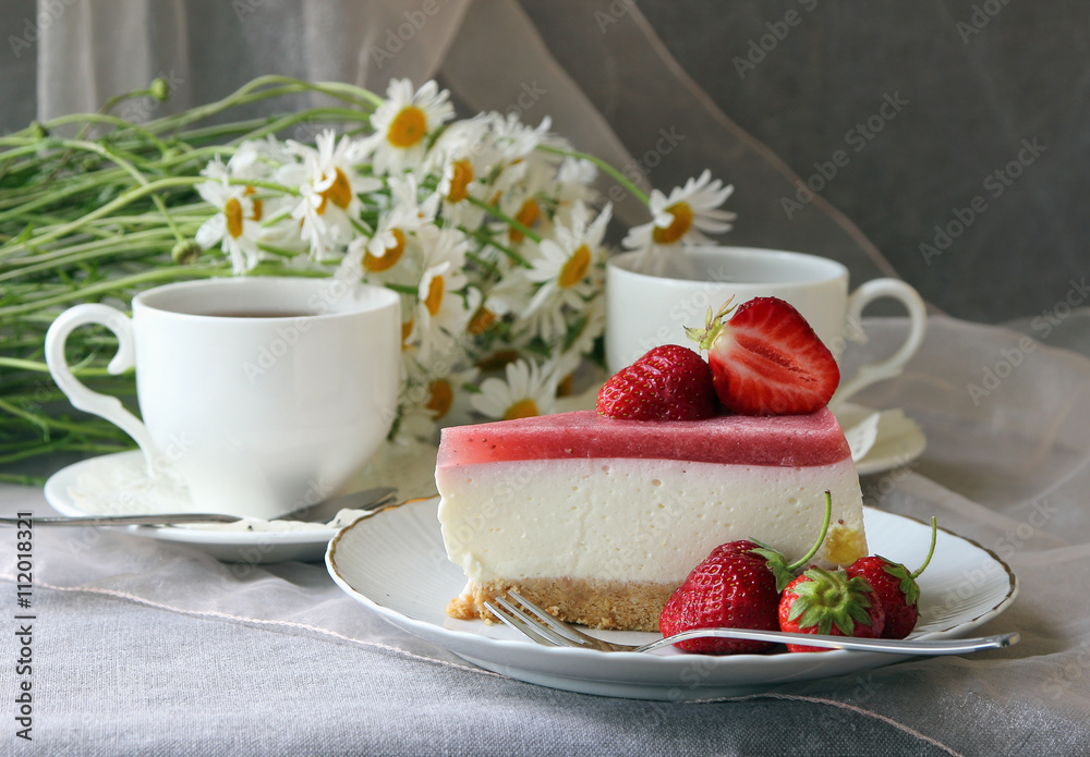 A piece of cake, white cup of tea and bunch of daisies.. A piece of cake, white cup of tea and bunch of daisies..