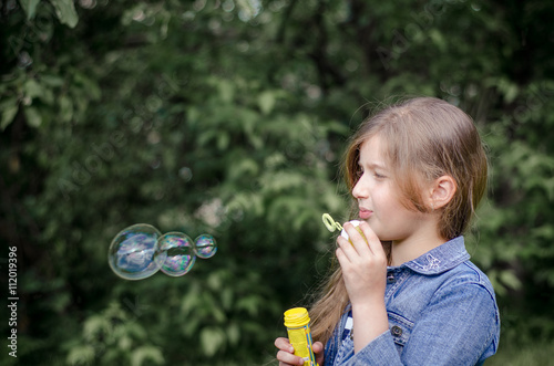 Portrait of cute lovely little girl blowing soap bubbles.