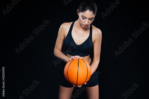 Serious beautiful young fitness girl with orange basketball ball