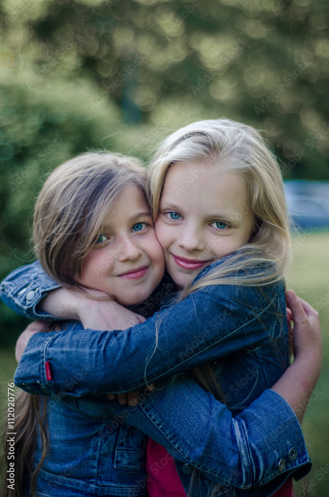 Brown and blond haired cute little girls friends smiling and hug Brown and blond haired cute little girls friends smiling and hug
