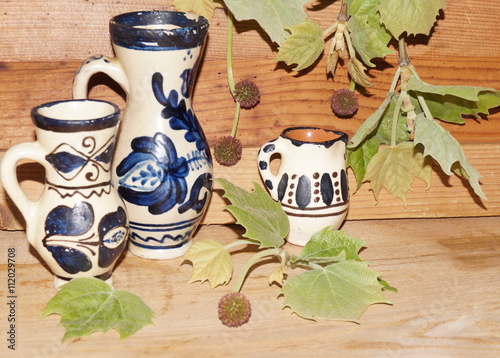 Romanian ceramics and sycamore leaves on wooden background 