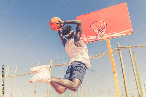 Basketball street player making a slam dunk outdoor  photo