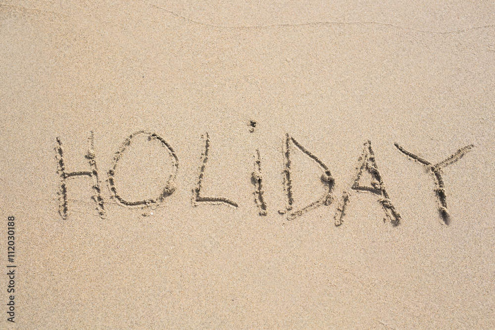 Fototapeta premium The word holiday in the sand.