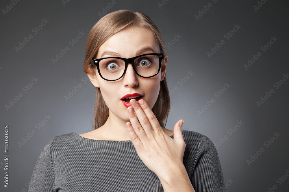 Wide-eyed astonished woman covering mouth with hand Wide-eyed astonished woman covering mouth with hand