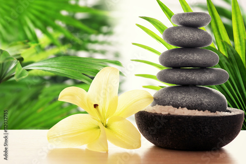 Composition with spa stones and lily on natural blurred background