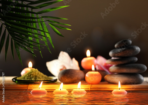 Composition with spa stones, flower and candles in water on blurred background