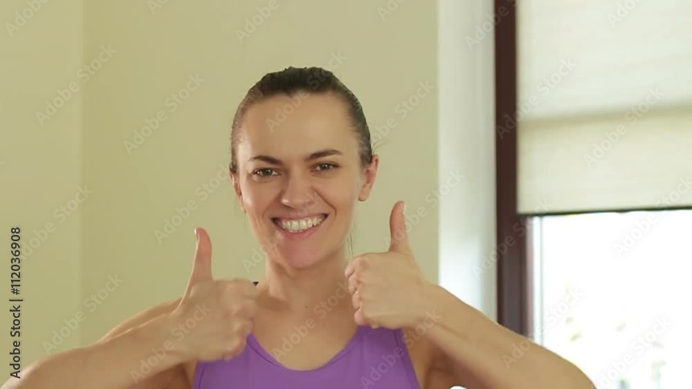 Portrait of young smiling sporty woman with thumbs up, slow motion