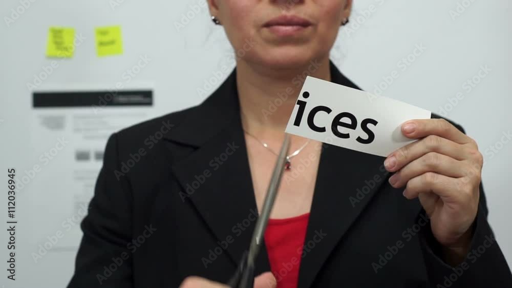 Female office worker or business woman cuts a piece of paper with the word prices on it as a price reduction business concept. Female office worker or business woman cuts a piece of paper with the word prices on it as a price reduction business concept.