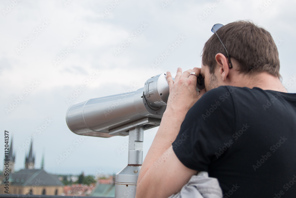 man carefully looking through binoculars