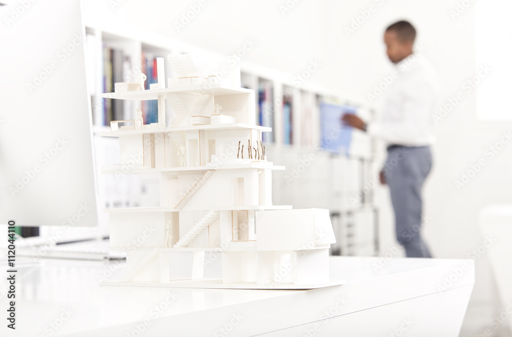 Architectural model on desk in an office with man in the background Architectural model on desk in an office with man in the background