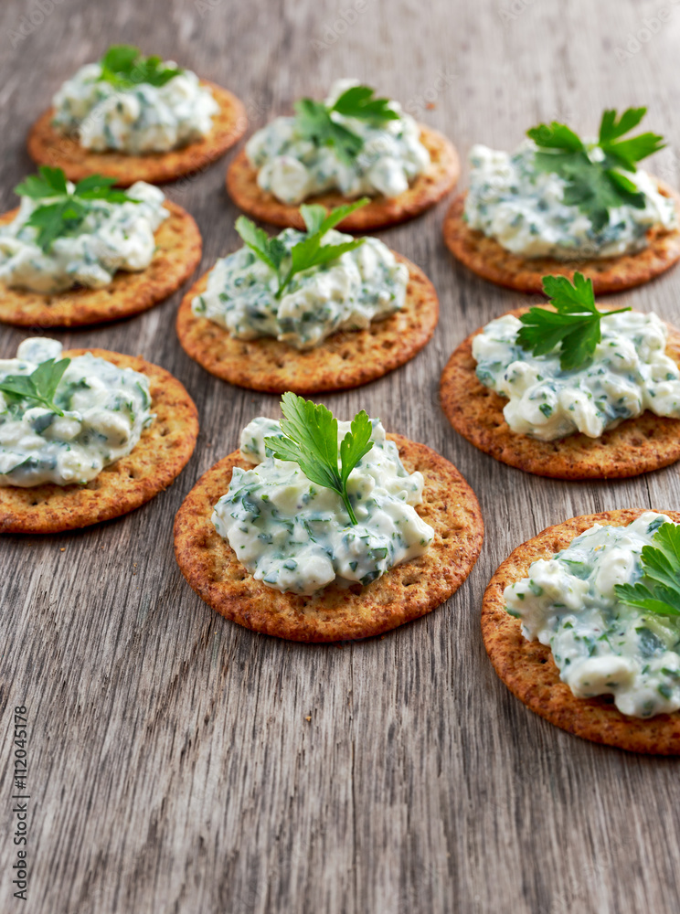 Bisquit cracker appetizers with cottage chees and parsley topping