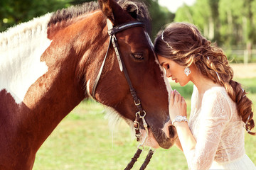 Sensual photo of young beautiful bride hugging a horse