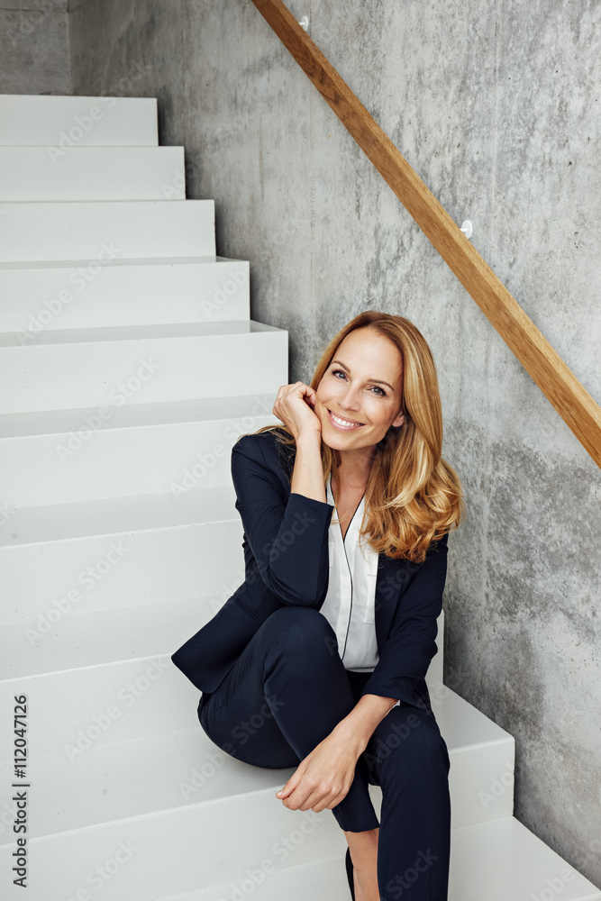 Portrait of smiling businesswoman sitting on stairs Portrait of smiling businesswoman sitting on stairs