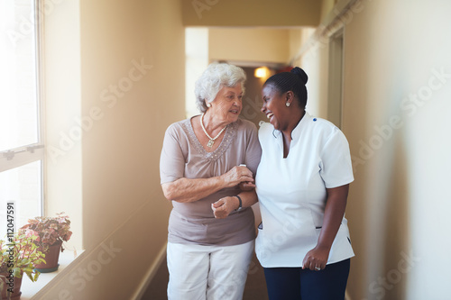 Murais de parede Happy female caregiver and senior woman walking together