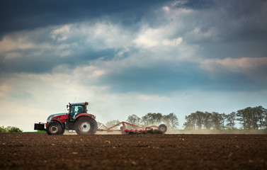 Acrylglasbilder Traktor Traktor pflügt und besprüht das Feld  © ValentinValkov