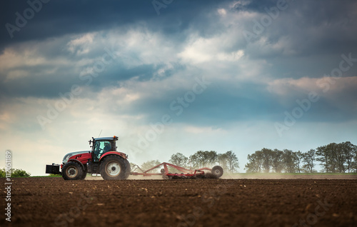 Canvas Print Farming tractor plowing and spraying on field