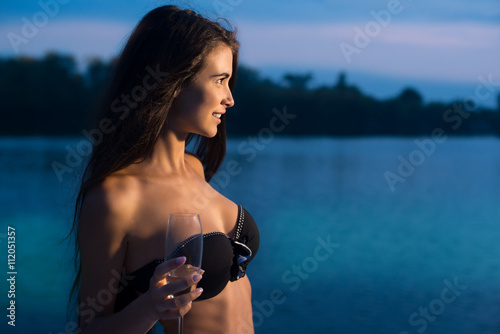Smiling girl with wineglass. Young lady on sea background. Celebrating birthday at sea resort. Youth and beauty.