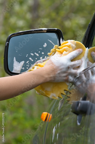 hand of woman washing car with sponge