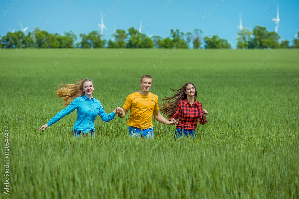 Obraz premium Young happy Friends running on green wheat field