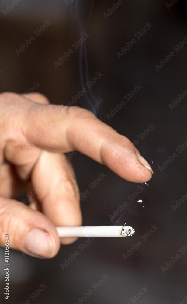 smoking a cigarette in his hand on black smoking a cigarette in his hand on black