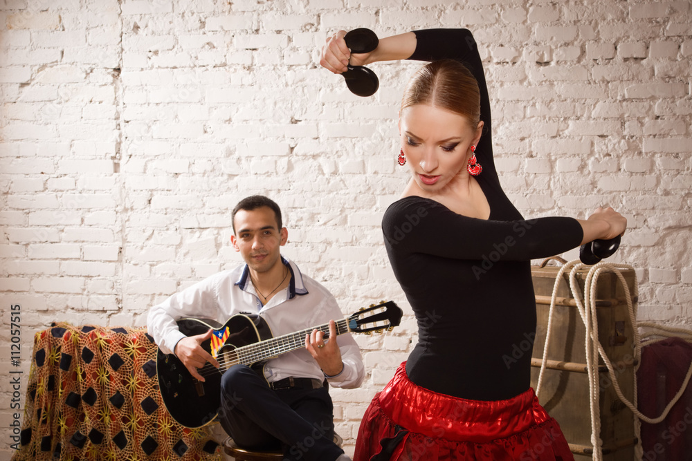 Naklejka premium Young woman dancing flamenco and a man playing the guitar