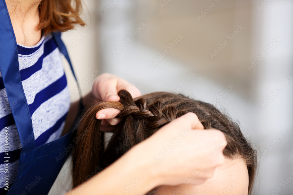Naklejka premium Professional hairdresser braiding clients hair