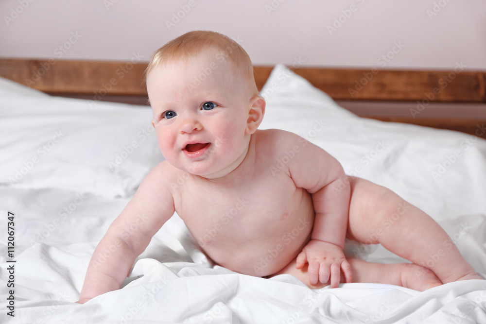 Adorable baby sitting on parents bed, close up Adorable baby sitting on parents bed, close up