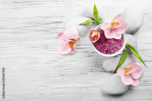 Spa stones, sea salt and orchid flowers on wooden background