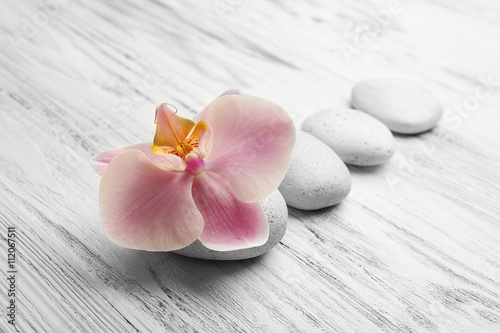 Spa stones and orchid flower on wooden background