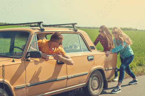 Young hipster friends on road trip on a car