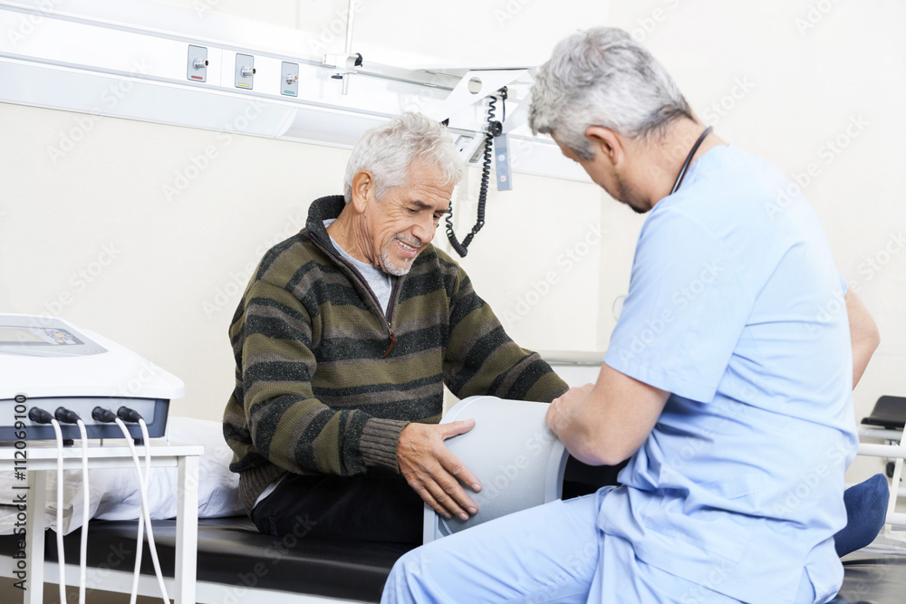 Obraz premium Physiotherapist Examining Senior Patient On Bed