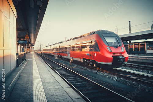 Canvas Print Beautiful railway station with modern red commuter train at colorful sunset in Nuremberg, Germany
