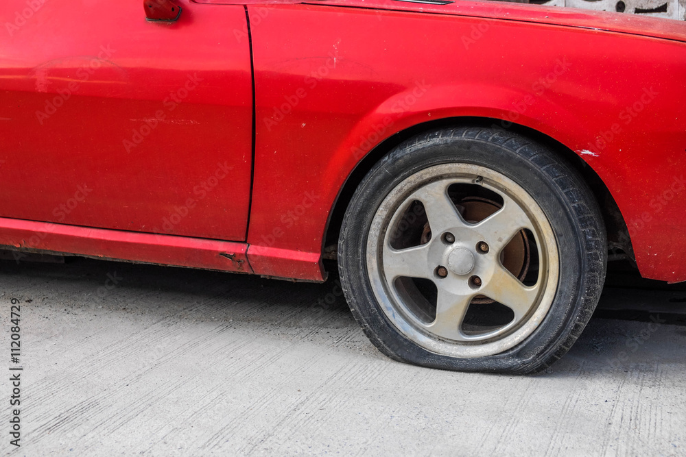 A tire of red old car was puncture