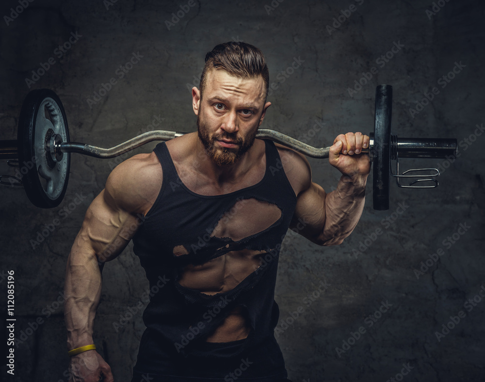 Portrait of bearded bodybuilder with barbell on his shoulder.
